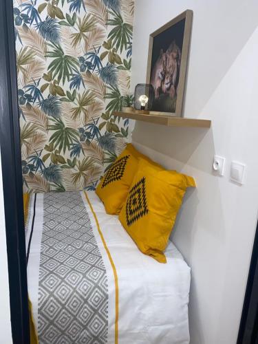 - un petit lit avec 2 oreillers jaunes dans l'établissement La Maison du Soleil, à Luxeuil-les-Bains