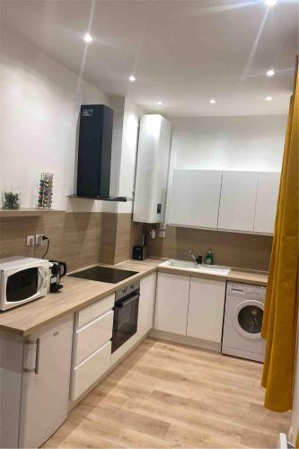 une cuisine avec des armoires blanches, un évier et un micro-ondes dans l'établissement La Maison du Soleil, à Luxeuil-les-Bains