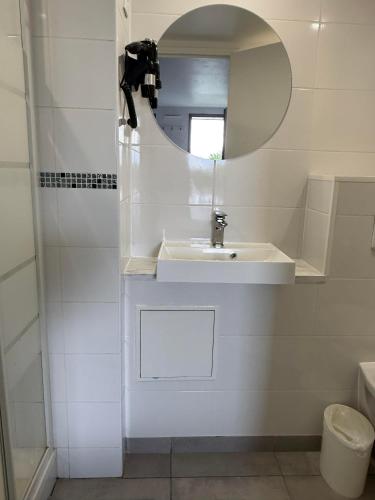 a white bathroom with a sink and a mirror at Fasthotel Roissy - Saint-Witz in Saint-Witz