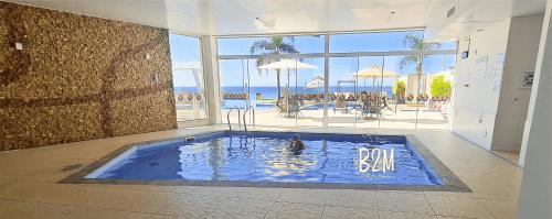 a swimming pool in a room with a view of the beach at Beto Carrero, pé na areia, piscina aquecida, Bali in Piçarras
