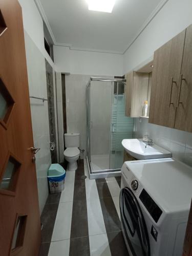 a small bathroom with a shower and a washing machine at Komi Luxury Maisonette in Kómi