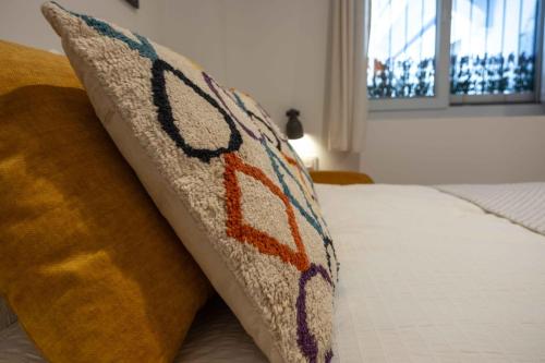 a pillow with a design on it sitting on a bed at Apartamentos El Aljibe in Badajoz