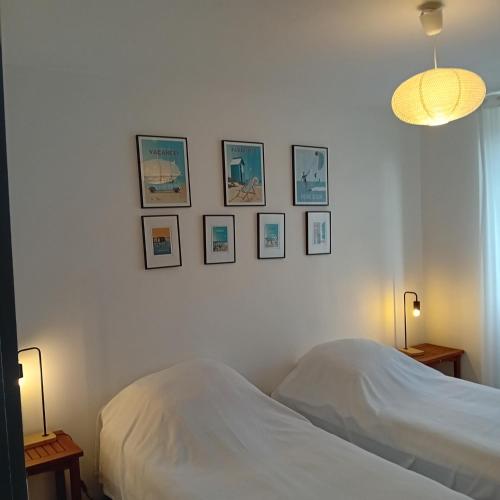 une chambre avec un lit et des tableaux au mur dans l'établissement 7 rue du Lest, à Pléneuf-Val-André