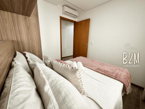 a bedroom with a bed with white pillows at Beto Carrero, pé na areia, piscina aquecida, Bali in Piçarras
