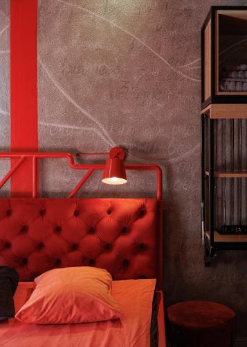 a bedroom with a red headboard and a red lamp at Masoch. Hotel & Cafe in Lviv