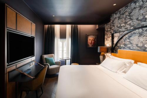 a hotel room with a bed and a flat screen tv at The Goethe Hotel - Small Luxury Hotels of the World in Rome