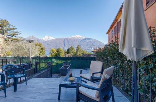 a patio with chairs and an umbrella and a table at LakeView LakeComo, CIPRESSO 2, 4Seasons, Terrace, 30m to Lake! by STAYHERE-LAKECOMO in Acquaseria