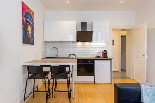 - une cuisine avec un comptoir et des chaises dans la chambre dans l'établissement L'Élégant - Charmant appartement 3 pièces proche Musée d'Art Moderne et Gare Centrale, à Strasbourg