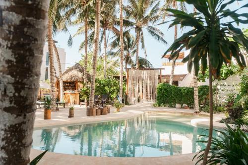 a swimming pool in a resort with palm trees at Hotel Boutique Can Cocal El Cuyo in El Cuyo