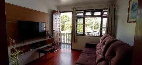 a living room with a couch and a large window at Quarto em apartamento próximo ao aeroporto in São José dos Pinhais