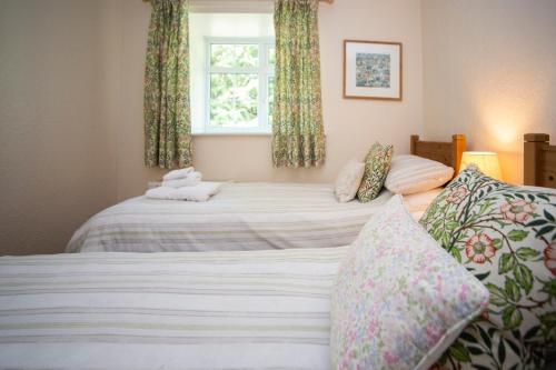 a bedroom with two beds and a window at Stable Cottage in Bardon Mill