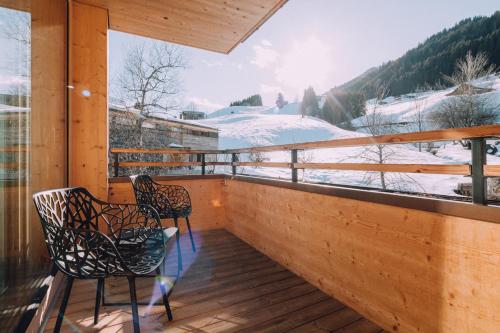 a balcony with two chairs and a view of snow covered mountains at Naturhotel Chesa Valisa in Hirschegg
