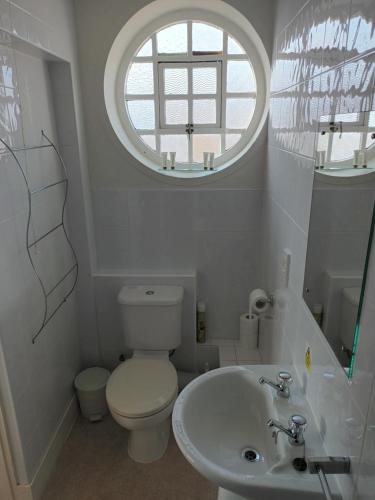 a bathroom with a toilet and a sink with a window at Royal Norfolk & Suffolk Yacht Club in Lowestoft