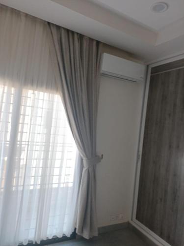 a window with a curtain in a room at Keur Dior Diagne in Thiès