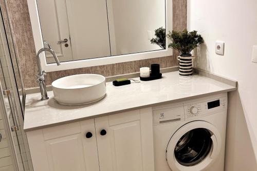 a bathroom with a sink and a washing machine at Stunning beach apartment in Almancil