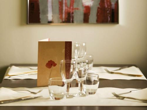 a table with wine glasses and a box on it at Hotel Mermoz Paris Le Bourget in La Courneuve