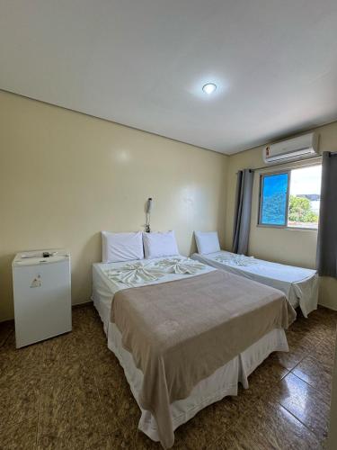 a hotel room with two beds and a window at Comodoro Hotel e Churrascaria in Floriano