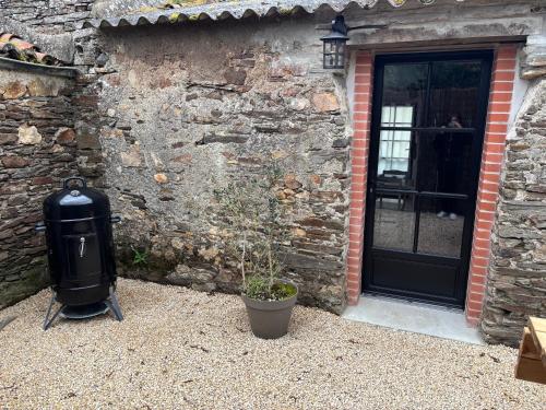 a trash can next to a stone building with a door at Gîte Héloïse in Le Pallet