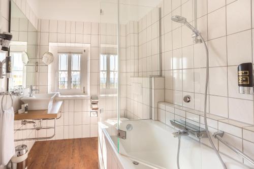 a white bathroom with a tub and a sink at Hotel Annaberg in Bad Dürkheim