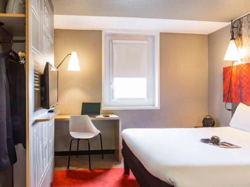 a hotel room with a bed and a desk and a window at ibis Paris porte de Bercy in Charenton-le-Pont