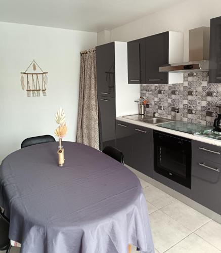 a kitchen with a table with a purple table cloth on it at Petit appartement à la campagne proche mer in Missillac