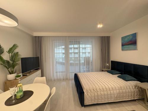 une chambre avec un lit, une table et une télévision dans l'établissement Lake View Sea Apartment Rogowo Pearl, à Rogowo