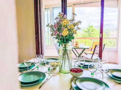 une table avec des assiettes et un vase avec des fleurs. dans l'établissement Apartment Les Estivales by Interhome, à Sanary-sur-Mer