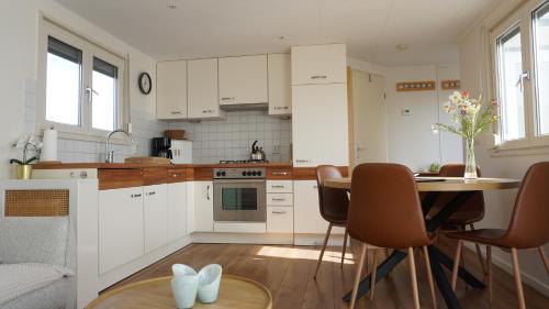 a kitchen with white cabinets and a table and chairs at Park Welgelegen, bungalow 28 in Cadzand