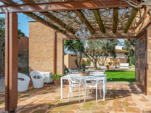 a patio with a white table and chairs under a pergola at Holiday Home Villa Chantal by Interhome in Pals