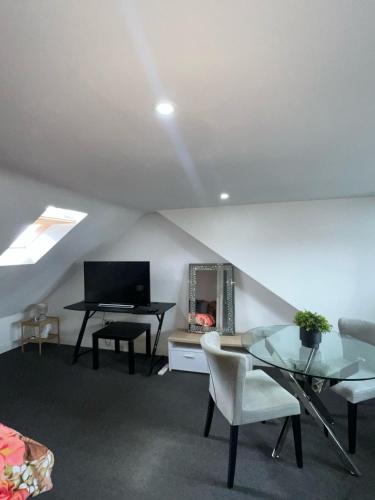 a attic living room with a table and a television at Modern Studio Flat In A Guest House In Basildon in Basildon