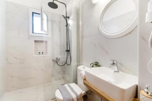 a white bathroom with a sink and a shower at Dionysia Rooms in Lefkada