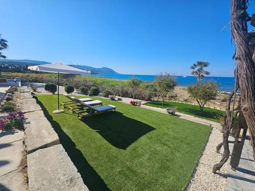 a park with a bench and an umbrella at Kallisti Beach & Spa Villa - A Luxury Seaside Retreat in Lachi