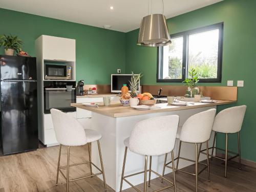 - une cuisine avec des murs verts et un îlot de cuisine avec des chaises blanches dans l'établissement Holiday Home Ty Heol by Interhome, à Pléneuf-Val-André