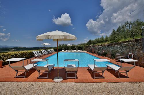 a swimming pool with chairs and an umbrella and a pool at Fattoria di Cinciano in Poggibonsi