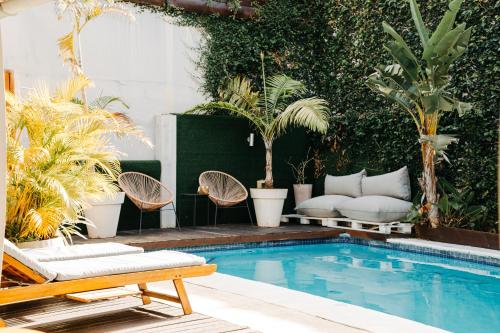 a pool with chairs and a couch in a yard at Joli Guesthouse in Maputo