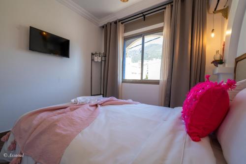 a bedroom with a bed with a pink pillow on it at Casa maravillosa in Chefchaouene