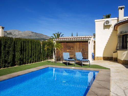 a swimming pool with two chairs next to a house at Holiday Home Lola by Interhome in Orba