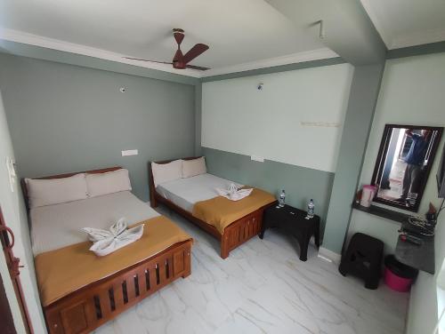 a small bedroom with two beds and a mirror at Sri Aksha Residency in Alāndurai