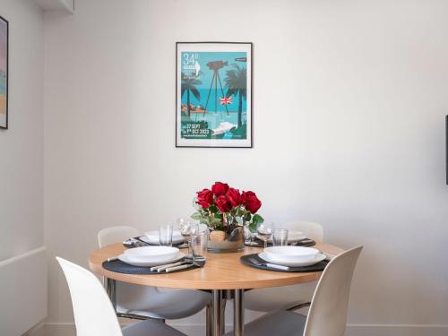 une table à manger avec des chaises blanches et une photo sur le mur dans l'établissement Apartment Le Triskel by Interhome, à Dinard