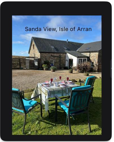 a table with two chairs and a table with wine glasses at Sanda View, Isle of Arran in Sliddery