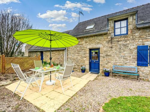 un patio avec une table, des chaises et un parasol dans l'établissement Holiday Home Maison de Kerguen by Interhome, à Ploemeur