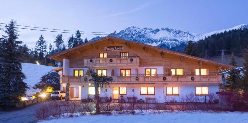 a large wooden house in the snow at night at Pension Aloisia in Scheffau am Wilden Kaiser