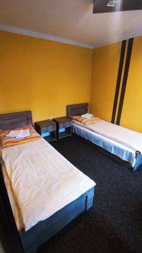 two beds in a room with yellow walls at Kompleks Rekreacyjno-Wypoczynkowy i Restauracja STRUMYK in Jordanów
