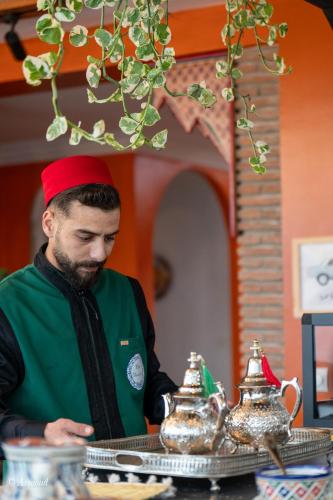 a man in a red hat standing at a table with tea pots at Casa maravillosa in Chefchaouene