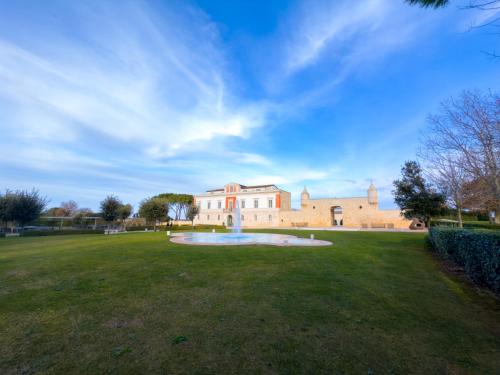a large building with a fountain in the middle of a field at Relais Il Santissimo in Turi