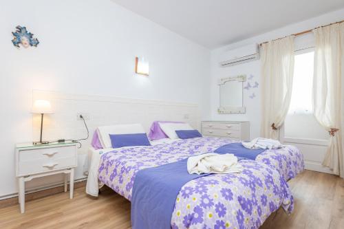a bedroom with two beds with blue and purple sheets at Sol in Port d'Alcudia