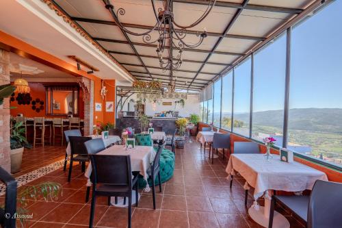 a restaurant with tables and chairs and large windows at Casa maravillosa in Chefchaouene