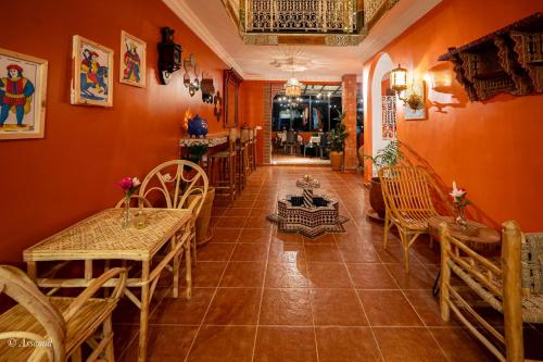 a dining room with orange walls and tables and chairs at Casa maravillosa in Chefchaouene
