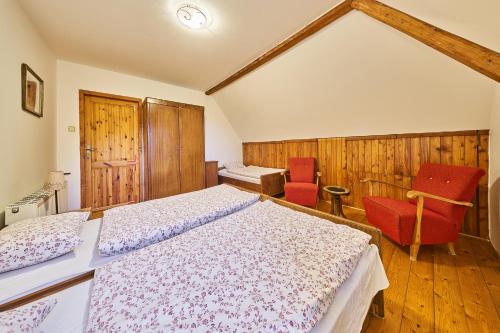 a bedroom with a bed and two red chairs at Horská chalupa U Hančilů in Pec pod Sněžkou