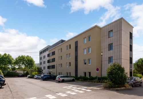 a large building with cars parked in a parking lot at B&B HOTEL Montpellier Centre Le Millénaire in Montpellier